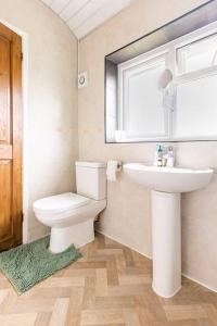 a bathroom with a toilet and a sink and a window at Spacious 3BHK near Heathrow in Cranford
