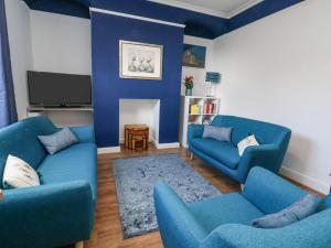 sala de estar con 2 sofás azules y TV en Oneofour en Chester