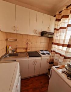 a small kitchen with white cabinets and a sink at Apartmani M br5 in Topola