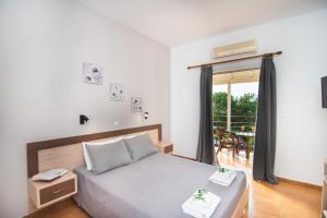 ein Schlafzimmer mit einem Bett und einem Balkon in der Unterkunft Sandy Beach Studios in Kavos