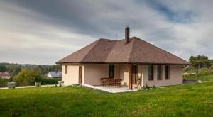 una pequeña casa blanca en una colina de hierba en Penzion - VILA VERI 1, en Ostrava