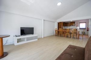 uma sala de estar com uma televisão e uma mesa e cadeiras em Guest House Ribeirinho - Alojamento local em Miranda do Corvo