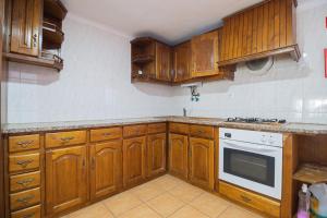 uma cozinha com armários de madeira e um fogão em Guest House Ribeirinho - Alojamento local em Miranda do Corvo
