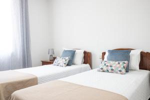 een slaapkamer met 2 bedden en kussens erop bij Guest House Ribeirinho - Alojamento local in Miranda do Corvo