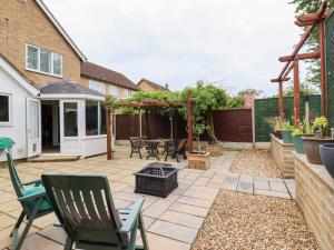 a patio with a grill and chairs and a fence at 23 Brandeston Close in Sudbury
