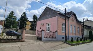 a pink house with a black roof and a fence at Urban Haven in Subotica