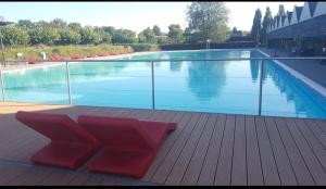a large swimming pool with red chairs on a wooden deck at Au chant des oiseaux in Rochefort