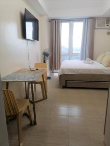 ein Hotelzimmer mit einem Bett, einem Tisch und einem Fenster in der Unterkunft Fast Wifi 400 Mbps at Kasara Urban Resort Residences with Netflix and Pool Access in Manila