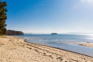 a beach with trees and the ocean on a sunny day at Casita Piñeiro estilo rural in Boiro +14 photos