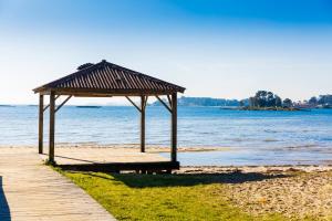 a picnic shelter on a beach next to the water at Casita Piñeiro estilo rural in Boiro