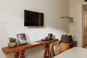 Casa Manor Boutique Hotel في تيفات: غرفة مع طاولة خشبية وتلفزيون على الحائط