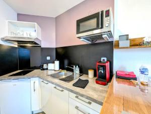 eine Küche mit einer Spüle und einer Mikrowelle in der Unterkunft Concept Appart'Hôtel - 202 in Saint-Brieuc