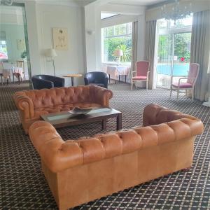 sala de estar con sofá de cuero marrón en Burley Court Hotel en Bournemouth