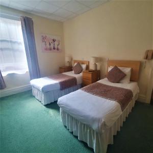 a hotel room with two beds and a window at Burley Court Hotel in Bournemouth