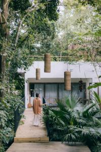 a woman walking down a wooden walkway in front of a house at Pousada Seis e Meia in Trancoso