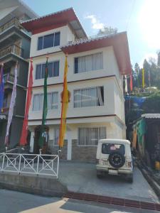 Sikkimese Inn في Ravangla: سيارة فان بيضاء متوقفة أمام مبنى