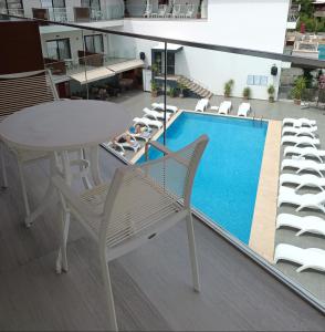 a balcony with a table and chairs and a swimming pool at Rhapsody Hotel & Spa Kalkan in Kalkan