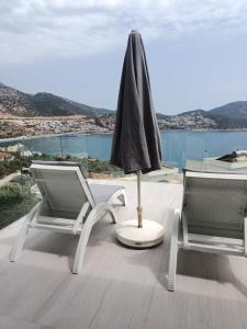 a patio with two chairs and an umbrella and a table at Rhapsody Hotel & Spa Kalkan in Kalkan