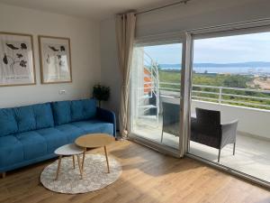 a living room with a blue couch and a balcony at Wellness Apartments Sunset in Zadar