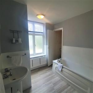 a bathroom with a tub and a sink and a bath tub at Burley Court Hotel in Bournemouth