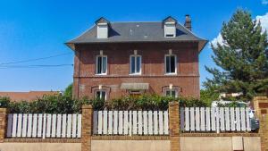 uma casa de tijolos com uma cerca branca em frente em Les Pommerets em Le Petit-Couronne