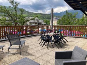 a patio with chairs and a table on a deck at Le Gaudissart 2 in Barcelonnette