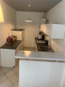 a kitchen with white cabinets and a white counter top at Maison cocoon avec jacuzzi privé vue Dordogne in Castillon-la-Bataille