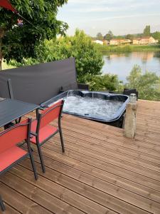 a hot tub on a deck with a table and a bench at Maison cocoon avec jacuzzi privé vue Dordogne in Castillon-la-Bataille