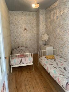 a bedroom with two beds in a room with wallpaper at Maison cocoon avec jacuzzi privé vue Dordogne in Castillon-la-Bataille