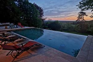 a swimming pool with chairs and a sunset in the background at Les Palissières in Mortagne-sur-Gironde