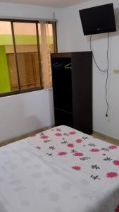 a bedroom with a bed with a white blanket with pink flowers at HOTEL DEL PARQUE VELEZ in Vélez