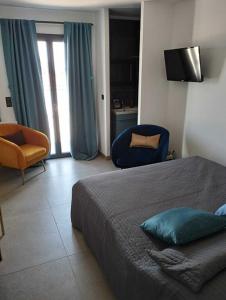 een slaapkamer met een bed en 2 stoelen en een televisie bij VILLA entre mer, montagnes, étangs et rivières in Ventiseri