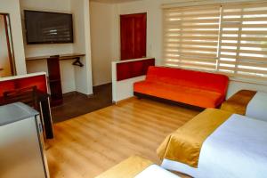 un salon avec un canapé rouge et une télévision dans l'établissement Hotel Villa Vianney, à Paipa