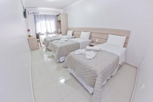 Habitación de hotel con 3 camas y espejo en North Hotel - Aeroporto, en Chapecó