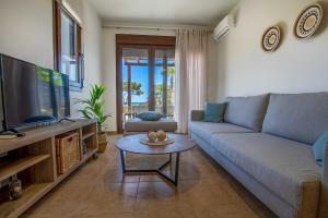 ein Wohnzimmer mit einer Couch, einem Fernseher und einem Tisch in der Unterkunft Villa Sunrise by the Sea in Kiotari