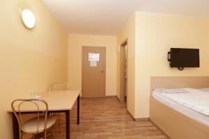 um quarto com uma mesa e uma cama e uma televisão em Beg Rooms em Maribor