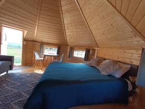 ein Schlafzimmer mit einem blauen Bett in einer Holzhütte in der Unterkunft Les Cabanes du Grand Nord in Pradines