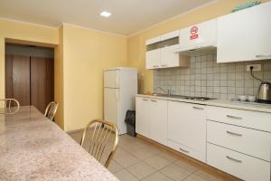 a kitchen with white cabinets and a table and a refrigerator at Beg Rooms in Maribor