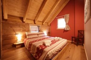 a bedroom with a bed with red walls and wooden floors at Casa Vacanze Le Falesie in Baceno