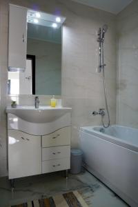 y baño con lavabo, bañera y espejo. en Helen.3 Apartment @Brown Luxury en Valea Lupului