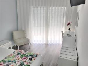 a bedroom with a bed and a chair and a window at Hotel Ancora Mar in Nazaré