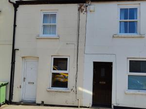 a white house with two windows and a door at Town Centre House with parking in Cheltenham