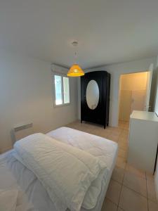 una camera con letto bianco e specchio di Appartement front de l'océan a Soulac-sur-Mer