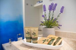 a bathroom counter with three bottles of sunscreen and a vase of flowers at La casa del pescatore in Cala Gonone