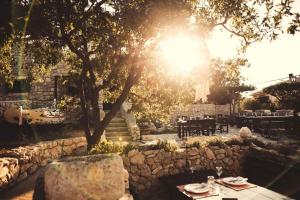 a table and chairs under a tree with the sun at Apartments Lipić in Posedarje