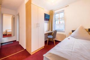 a bedroom with a bed and a desk and a window at Pension Lachmöwe in Zinnowitz