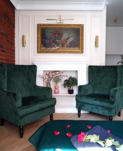 克拉科夫的住宿－Jacuzzi Spa Green Apartment，客厅配有两张绿色椅子和绘画作品
