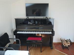 ein schwarzes Klavier mit einem TV darüber in der Unterkunft Ferienwohnung am Rhein in Koblach