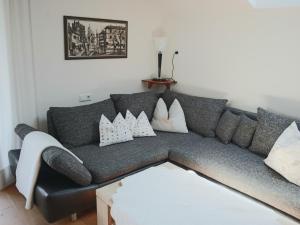 ein Wohnzimmer mit einem grauen Sofa und weißen Kissen in der Unterkunft Ferienwohnung am Rhein in Koblach