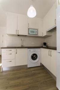 a kitchen with a washing machine and a microwave at APARTAMENTOS MAPAMUNDI in Badajoz